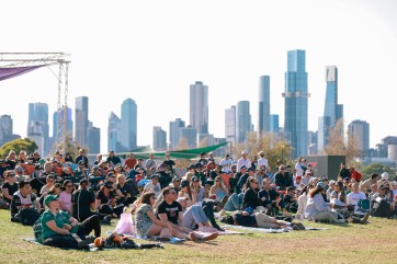 fans of f1 australian grand prix sitting on the grass with building in background